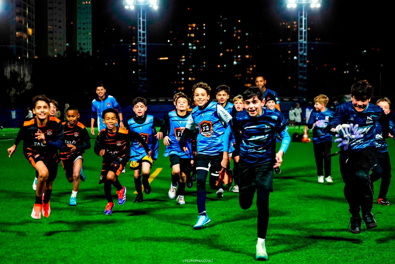 Grupo de atletas de base da FG Soccer Training correndo lado a lado em treino noturno