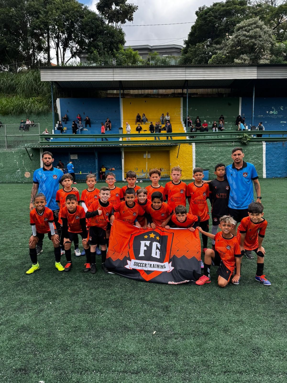 Equipe da FG Soccer Training reunida com a bandeira do projeto antes de uma partida